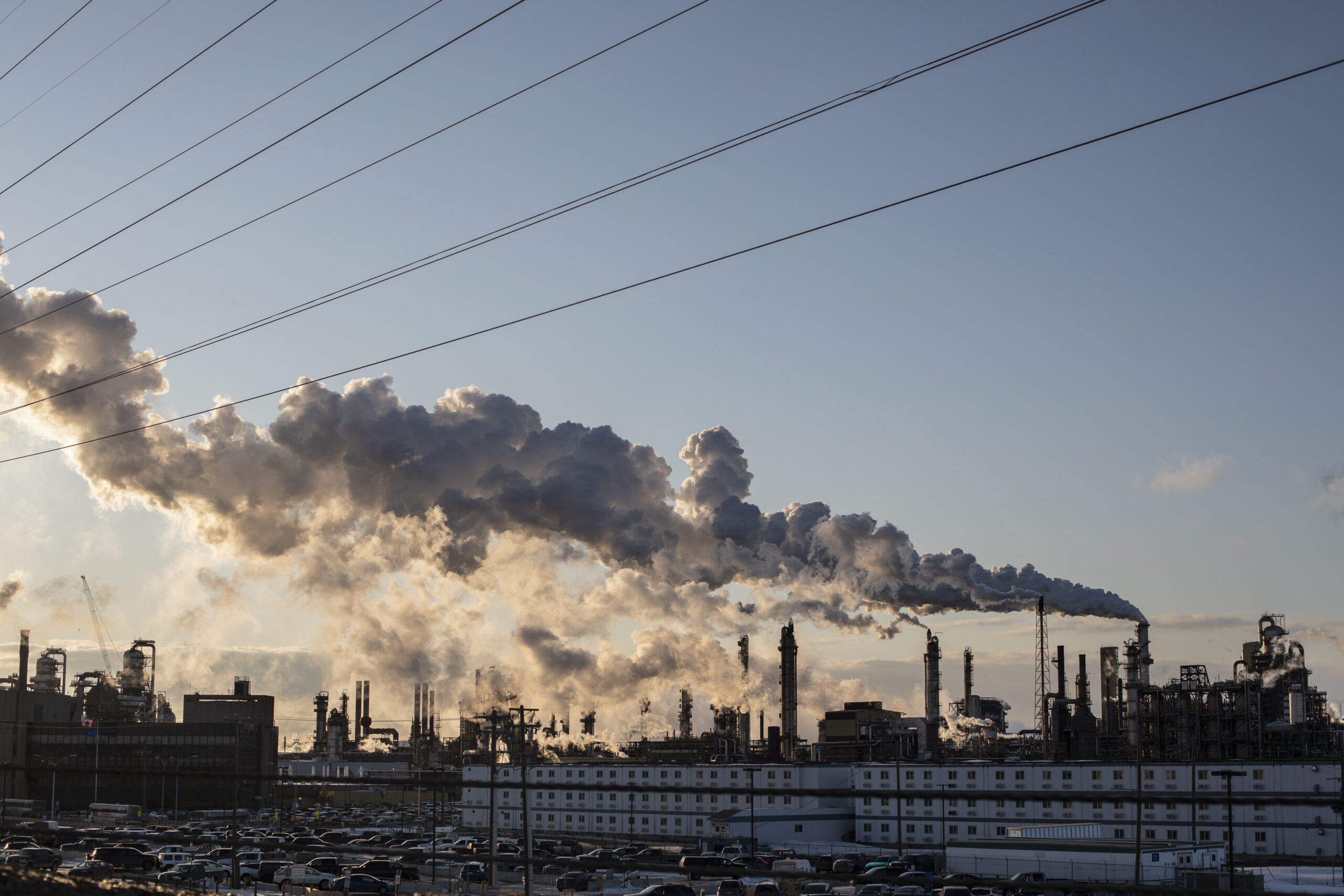 Oil and gas facilities and smoke against the dusk sky.