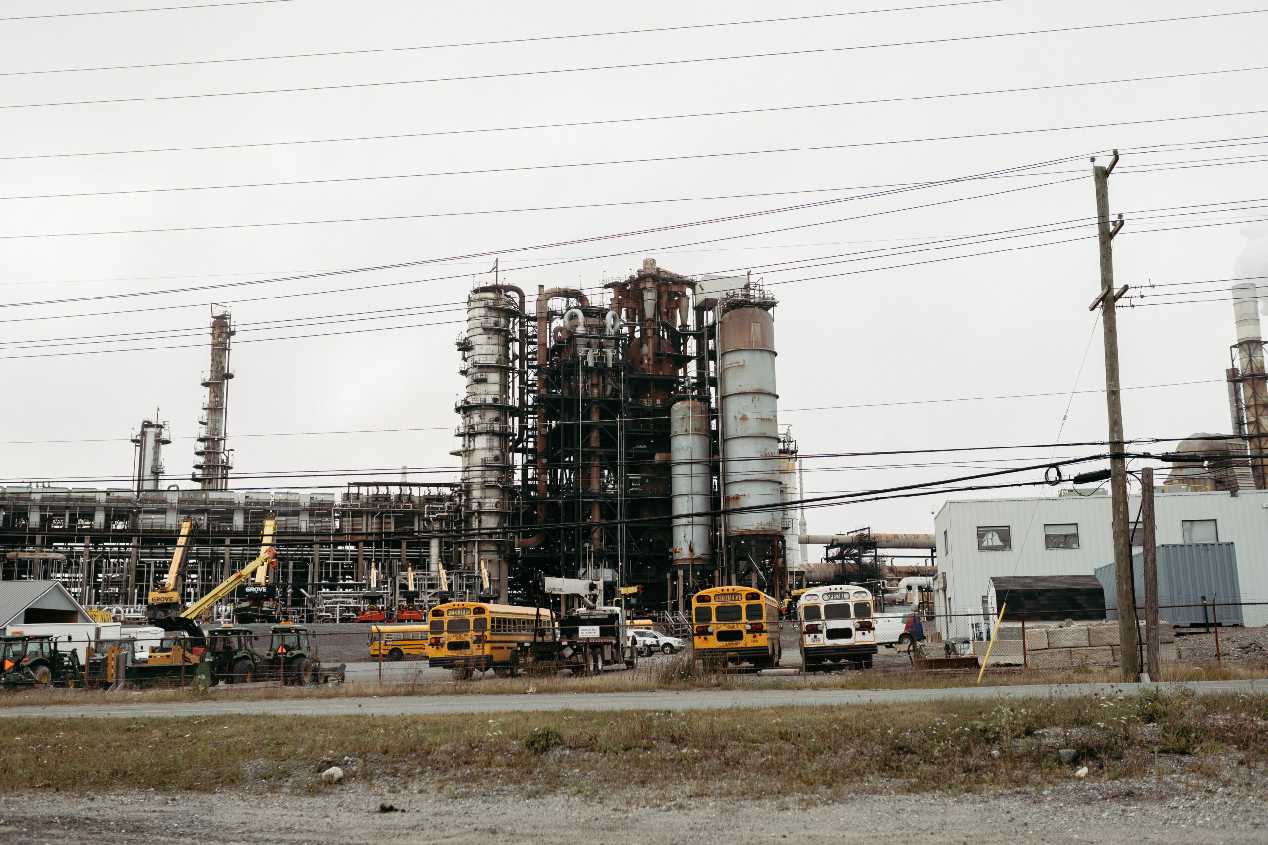 Smokestacks and other oil and gas infrastructure set against a grey sky.