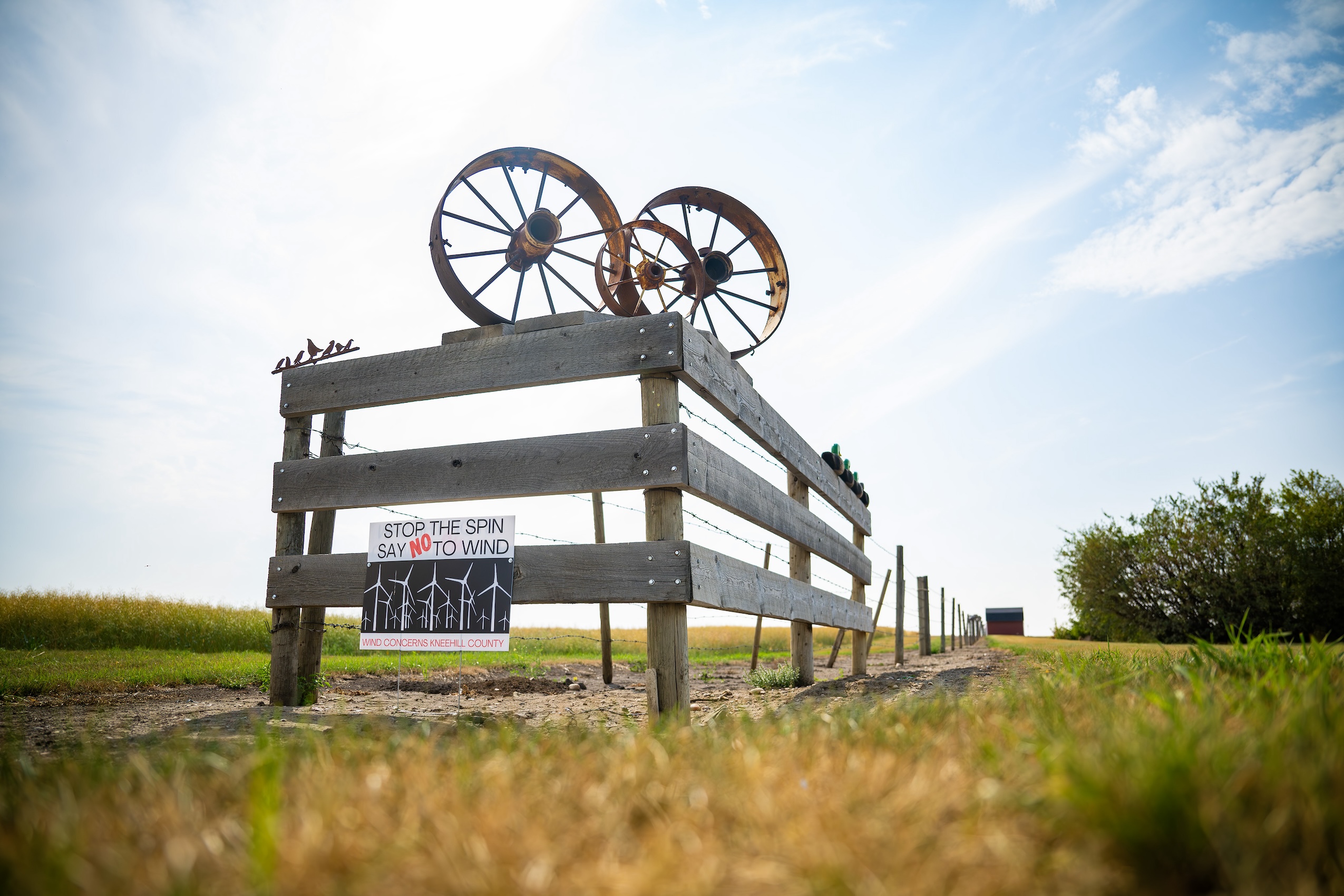 Some wooden fencing with metal sculptural elements and a sign that reads "stop the spin, say no to wind"