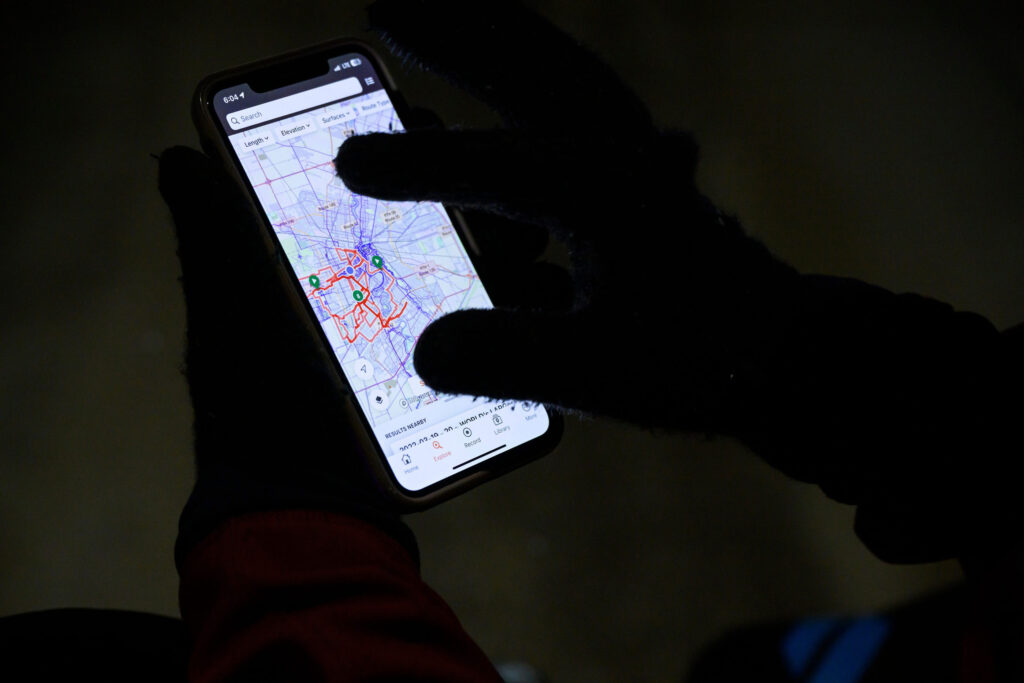 Winnipeg symphony orchestra bassist Daniel Perry's gloved hands hold a smartphone showing a bike route map