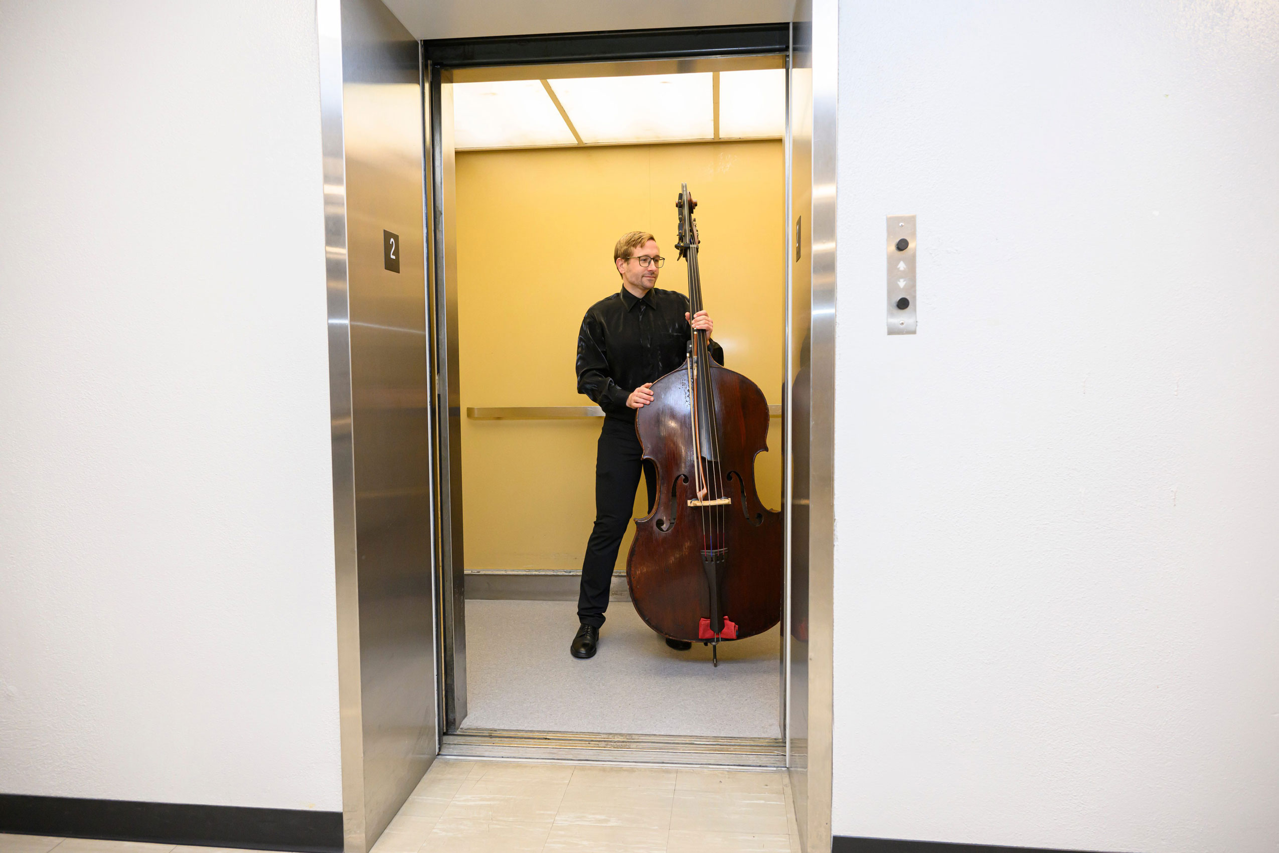 a bassist holds his instrument in an elevator