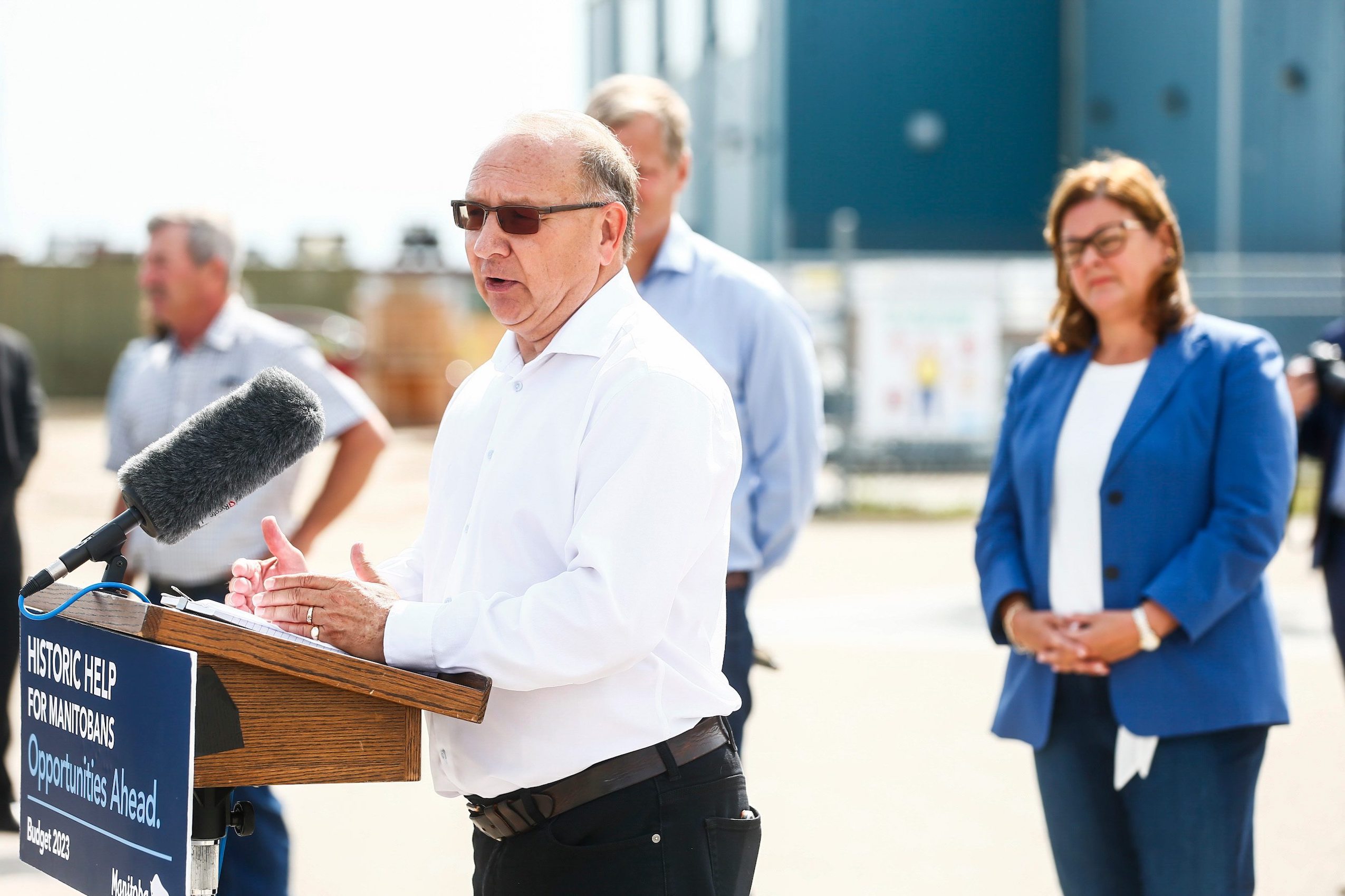 Daymon Guillas, president of the Potash and Agri Development Corporation of Manitoba, wears a white shirt as he speaks from a podium